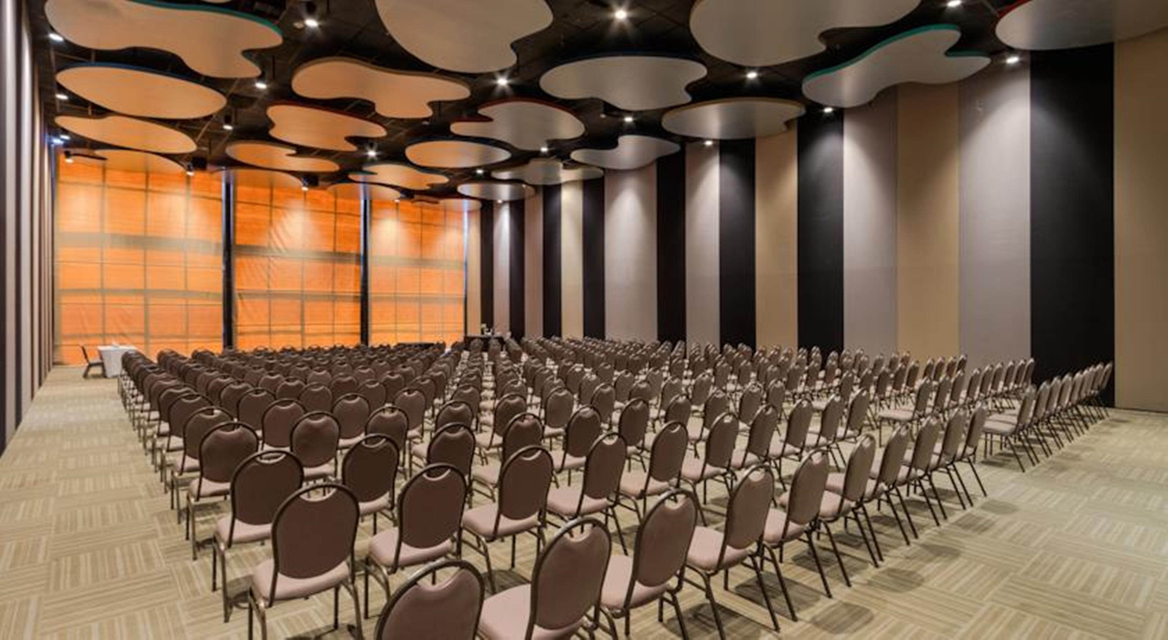 로열 튤립 브라질리아 알보라다 호텔 외부 사진 The photo shows a large conference or event space filled with numerous empty chairs arranged in rows. The chairs have a simple design, with cushioned seats and backs. The walls of the room are decorated with a combination of dark and light tones, and